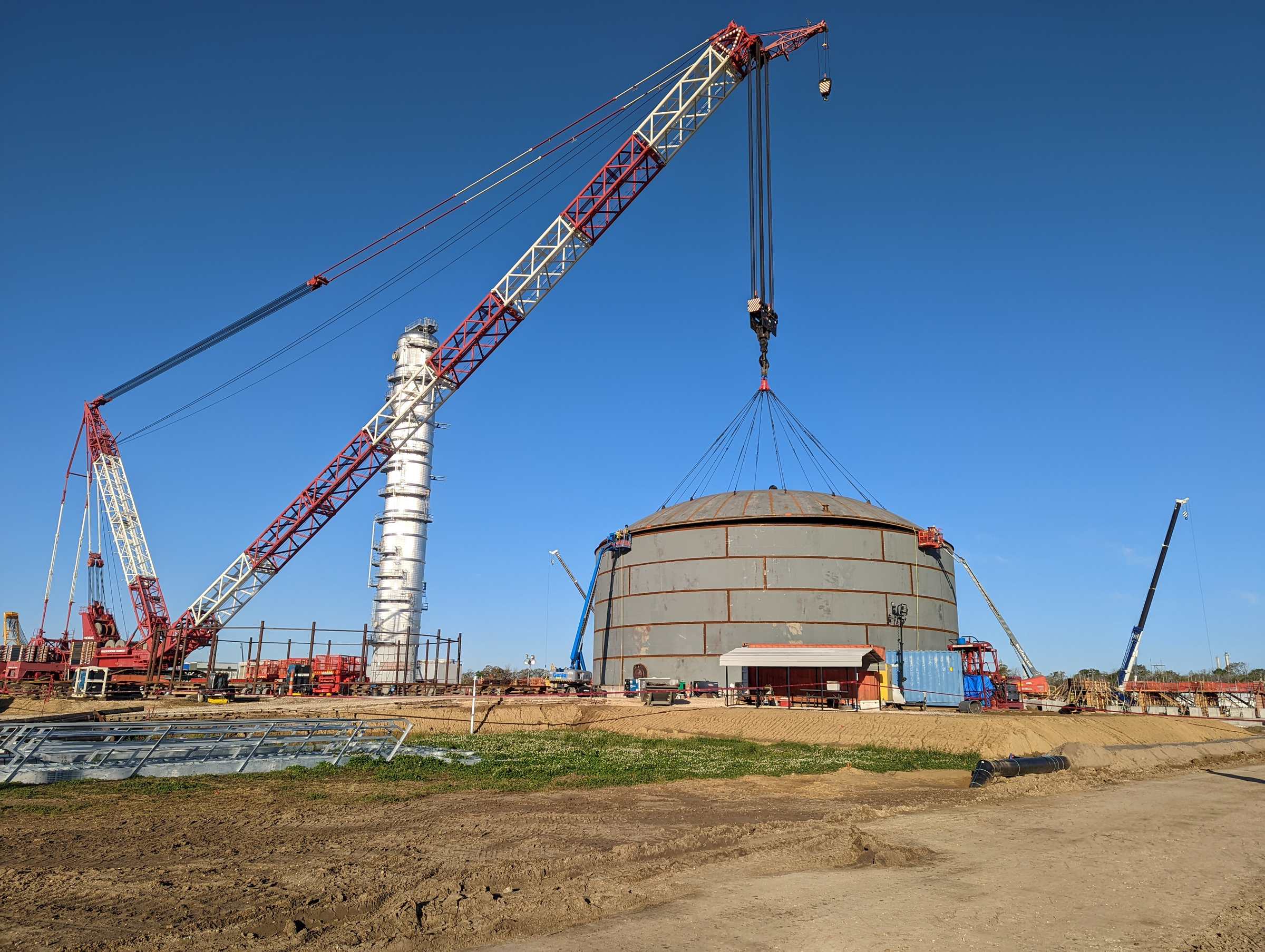 Crane lifting a storage tank roof section during PALA tank construction